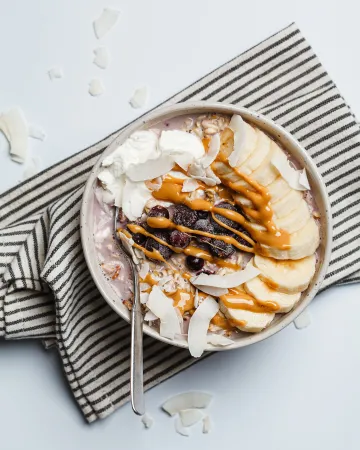 Overnight oats με μπανάνα, μούρα, νιφάδες καρύδας, σοκολάτα και βούτυρο ξηρών καρπών